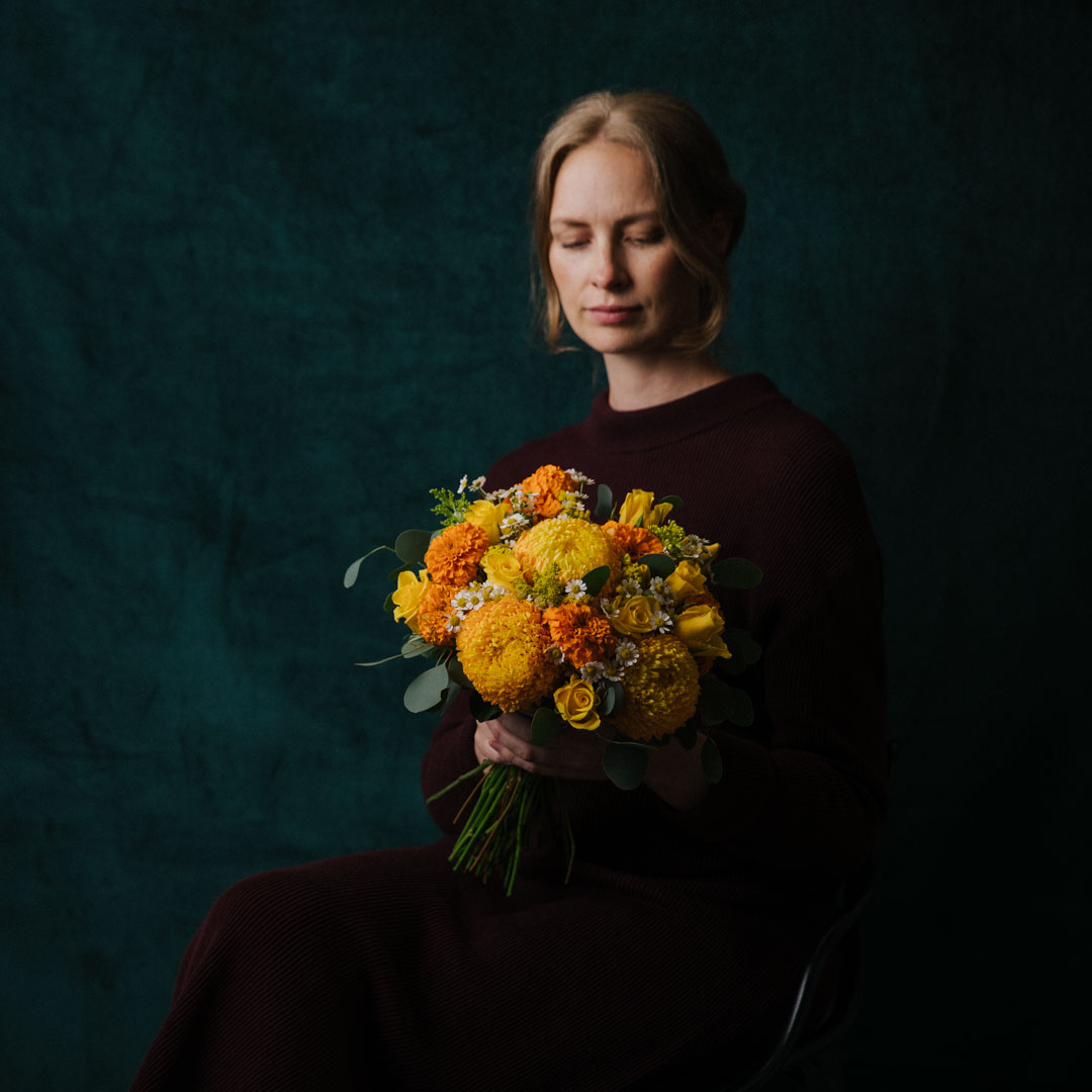 posy of yellow and orange fresh flowers held by a lady