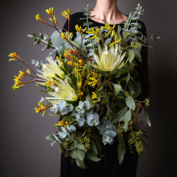 native flowers white and yellow with foliage arranged into a forward facing bouquet