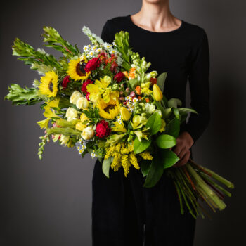 flowers yellow red and orange with foliage arranged into a forward facing bouquet